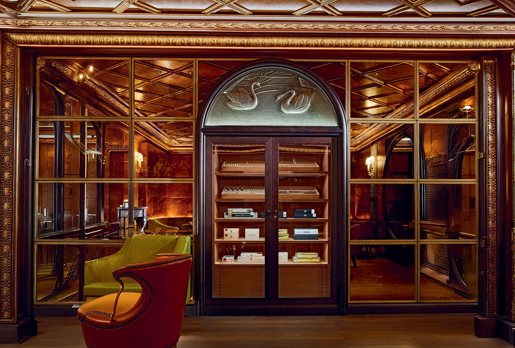Elegant cigar lounge with ornate wood detailing, glass doors, lounge chair, and humidor display