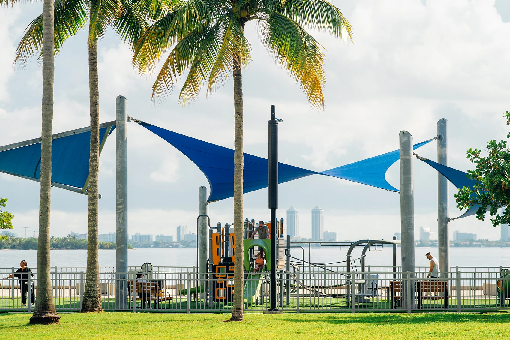 Families enjoying a shaded waterfront playground near a luxury Kempinski destination.