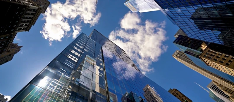 Upward view of glass high-rise architecture and blue sky representing urban growth and connectivity