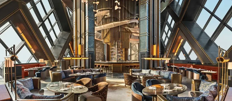 Elegant luxury dining lounge with dramatic architecture, round tables, upholstered seating, and a central bar