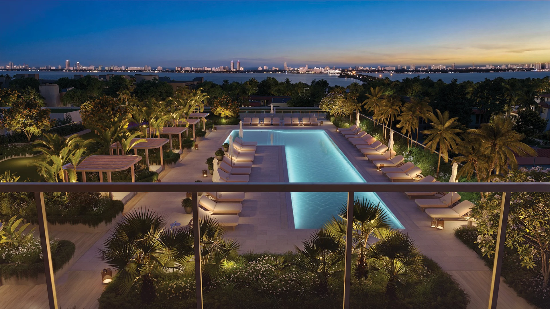 South pool area at Kempinski Residences Miami Design District illuminated at evening with Biscayne Bay and Miami skyline views