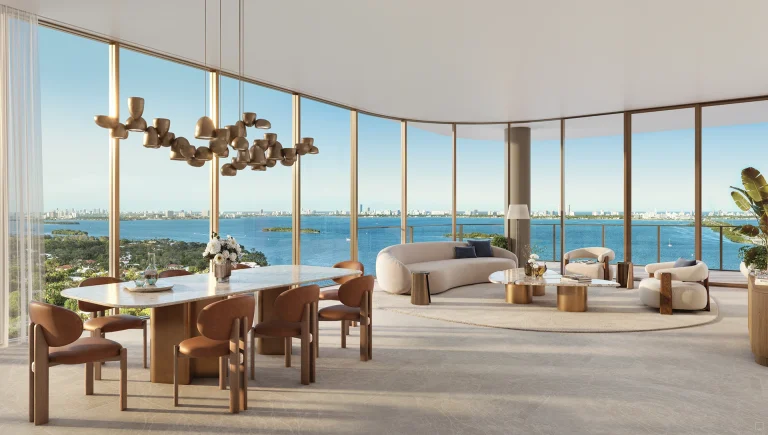 A refined living and dining room at Kempinski Residences Miami Design District featuring expansive floor-to-ceiling windows, curved glass walls, warm neutral interiors, a sculptural chandelier, dining table, lounge seating, private terrace access, and panoramic views of Biscayne Bay and the Miami skyline.