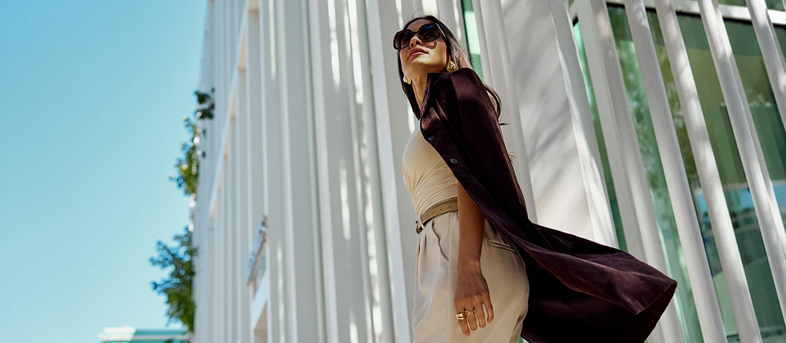 Woman in sunglasses walking beside modern white architecture in the Miami Design District