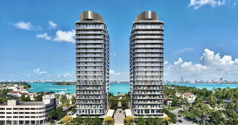Twin luxury residential towers rise above Miami's waterfront neighborhood, showcasing modern curved architecture with wraparound balconies against turquoise ...